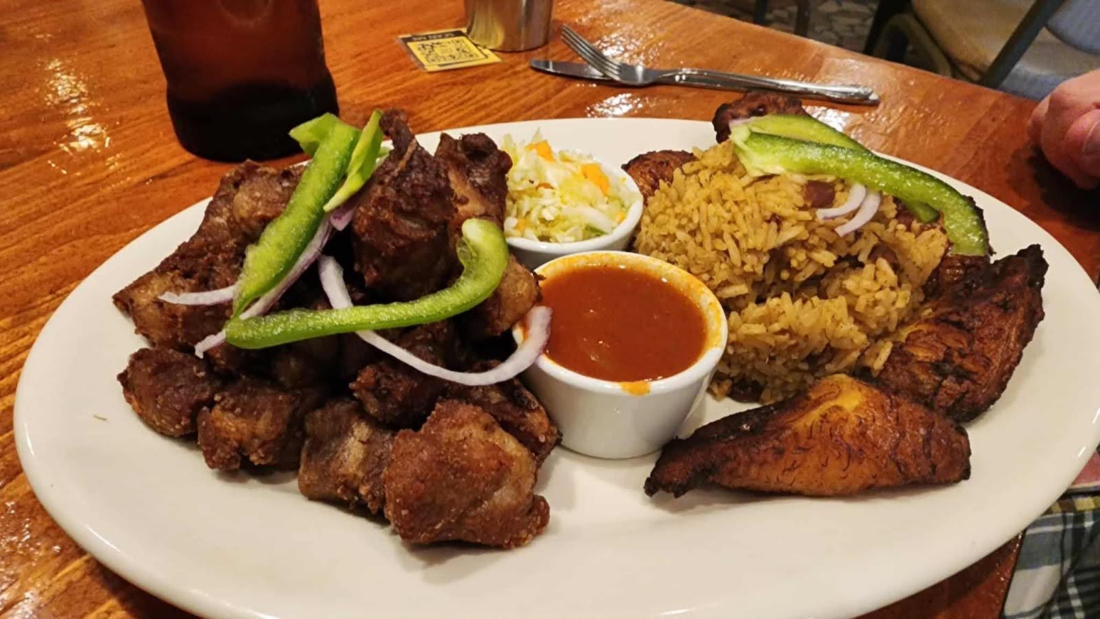 Prepped ingredients for Cajun jambalaya laid out on a kitchen counter, including  sausage, chicken, chopped vegetables, and herbs.
